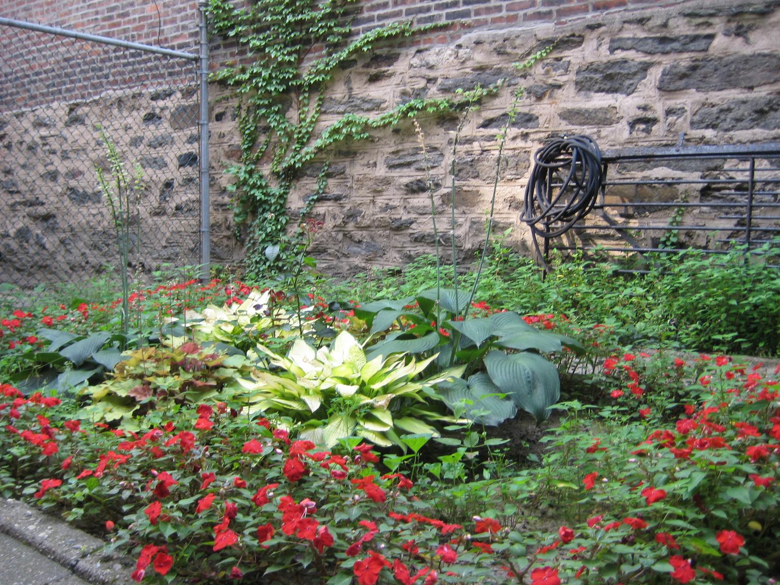Unit 1C private garden with red impatiens and hostas